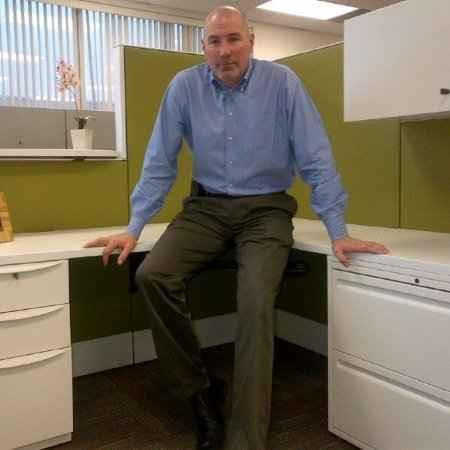 Photo of Mike, leaning on a colourful and modern office workstation.