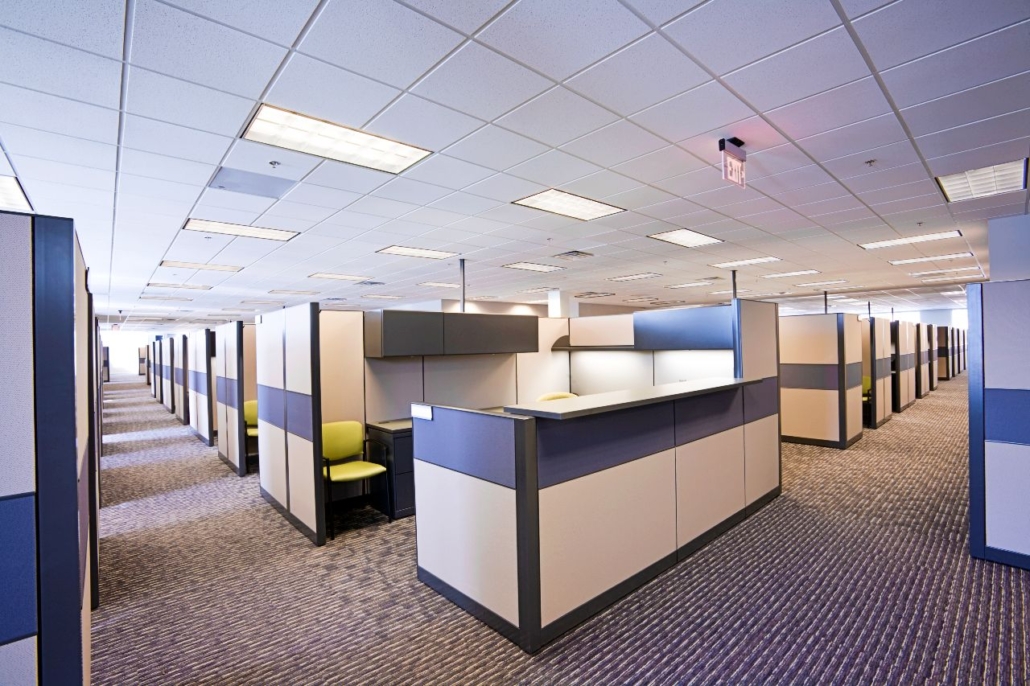 Neatly arranged grid of office workstations, in a brightly lit modern office space.